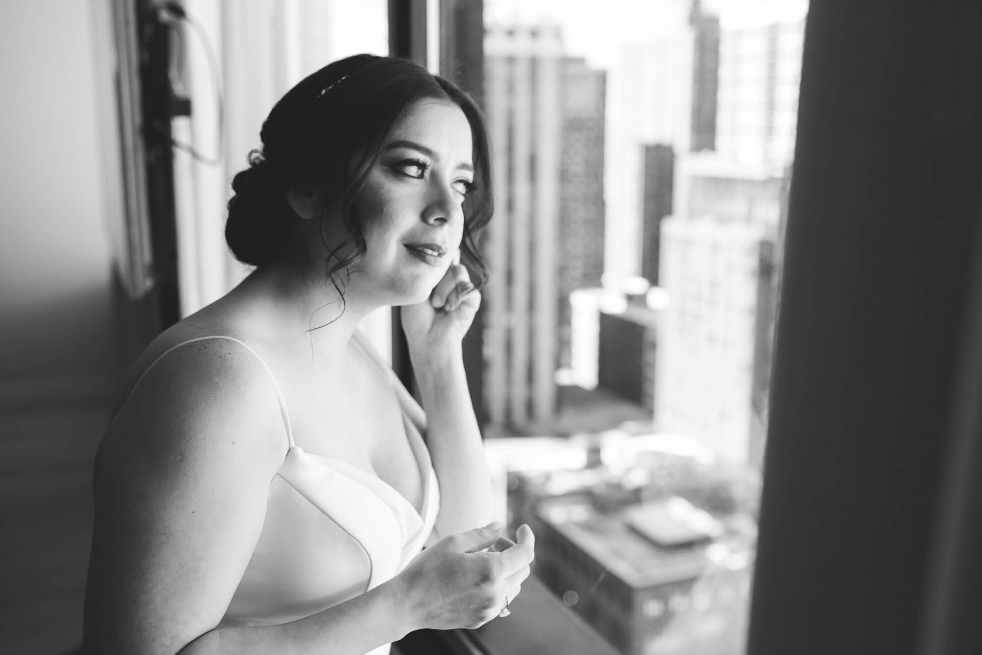 black and white portrait of bride getting ready in front of the window | oahu wedding hawaii family photography elle rose photo | glamorous destination winter wedding at thompson chicago 