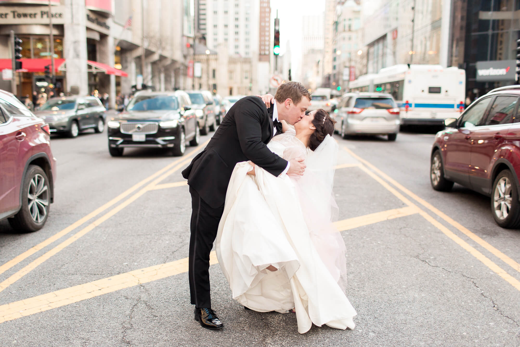 kissing bride and groom in the middle of busy city street | romantic elegant city wedding photography elle rose | oahu hawaii wedding photographer| destination black tie winter wedding in chicago illinois