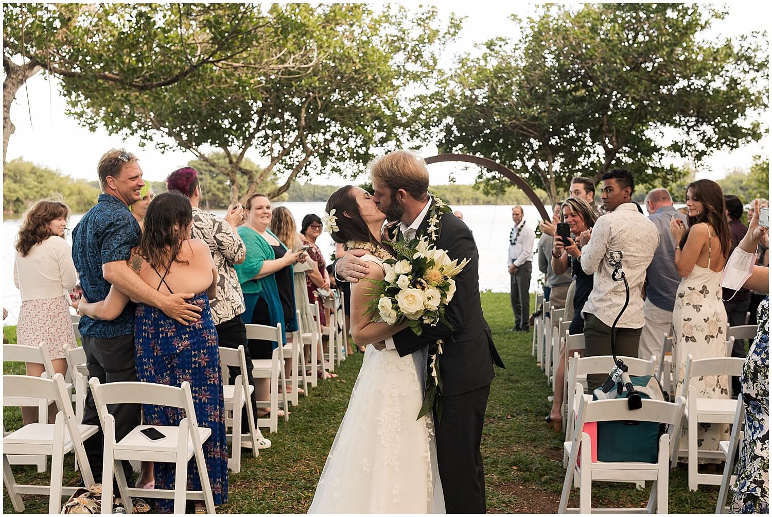 newly married couple share kiss after walking up the aisle by Elle rose photo
