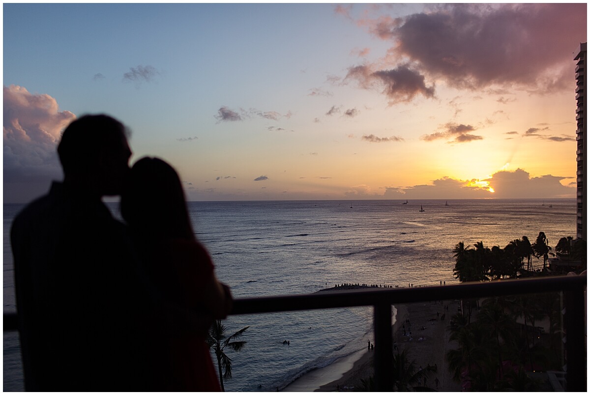 man and woman embrace as sun sets behind clouds at Waikiki anniversary session 