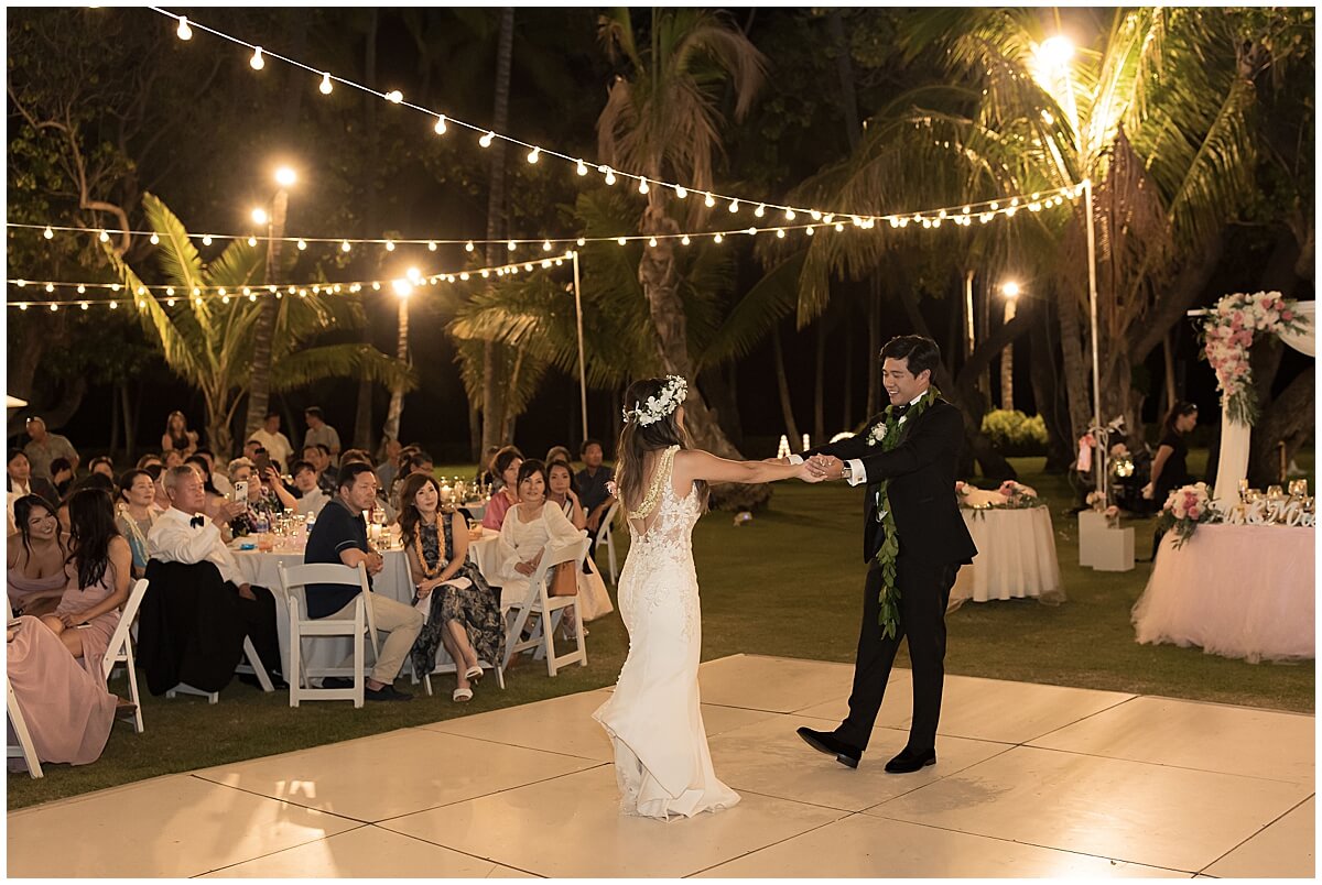 first dance with newly married couple at reception under string lights and on wood dance floor by oahu wedding photographer 